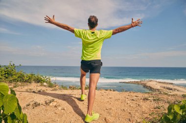 Okyanusa yakın tropik egzotik bir kayalıkta sporcu.