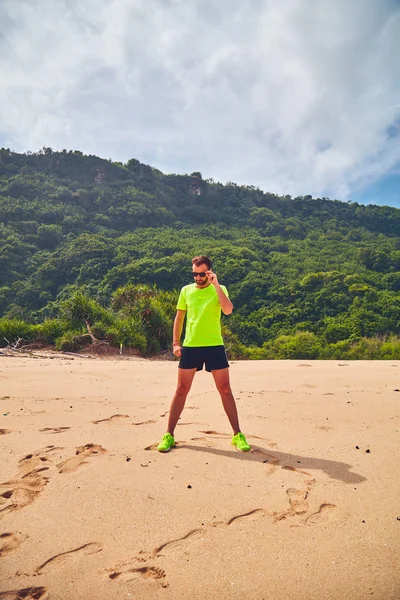 Esportista que se estende em uma praia tropical de areia . — Fotografia de Stock
