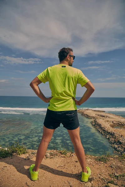 Deportista estirándose en un acantilado tropical exótico cerca del océano . — Foto de Stock