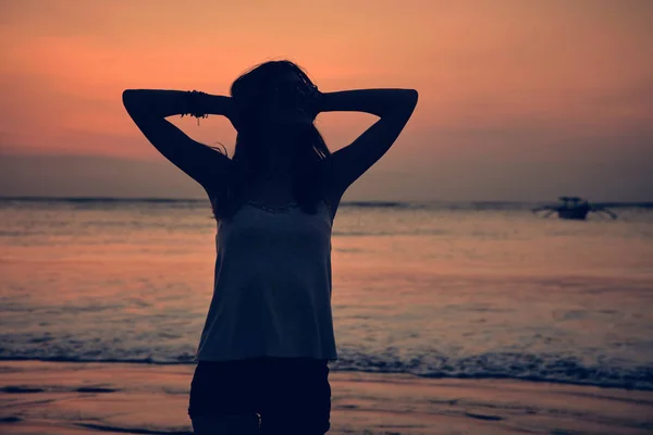 Silhuetten av en flicka i solnedgång / soluppgång tid över havet. — Stockfoto