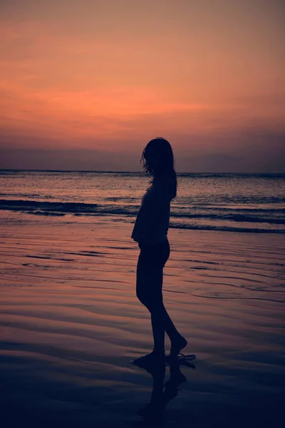 Silhueta de uma menina no pôr do sol / nascer do sol tempo sobre o oceano . — Fotografia de Stock