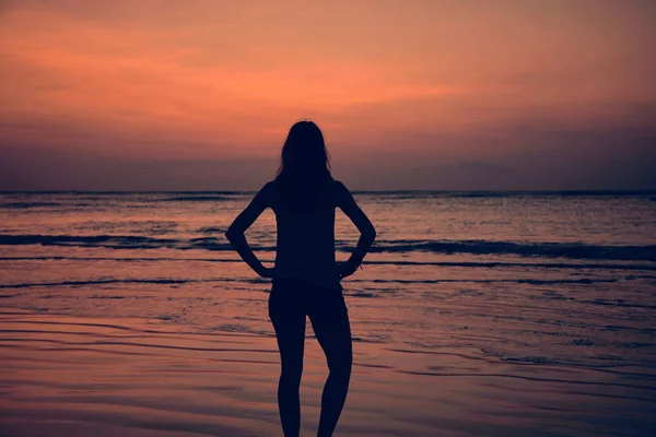 Silhueta de uma menina no pôr do sol / nascer do sol tempo sobre o oceano . — Fotografia de Stock