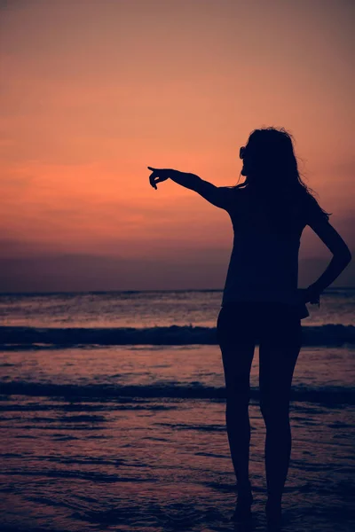 Silhueta de uma menina no pôr do sol / nascer do sol tempo sobre o oceano . — Fotografia de Stock