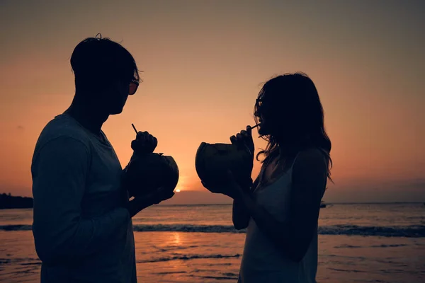 Par dricka cocnut juice medan du tittar på solnedgången över — Stockfoto