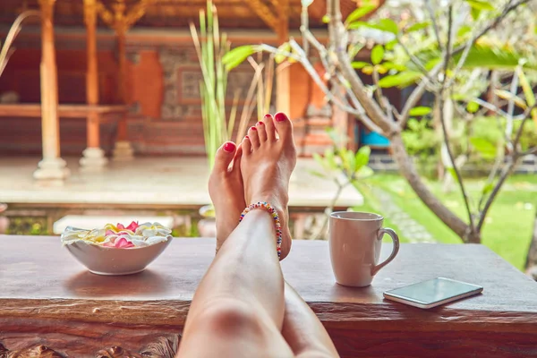 Pieds de femme sur un bureau dans une cour tropicale . — Photo