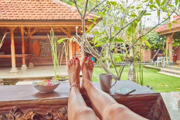 Piedi di donna su una scrivania in un cortile tropicale . — Foto Stock