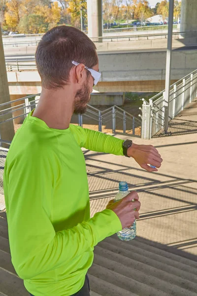 スポーツマンは大都会の橋の上で腕時計を見ている. — ストック写真