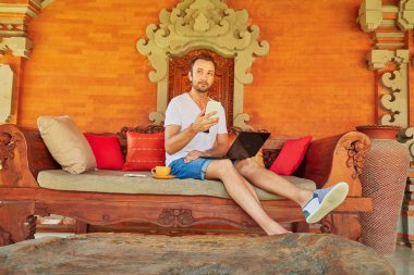 Bir ev verandada kahve / çay ve dizüstü bilgisayar ile Man.