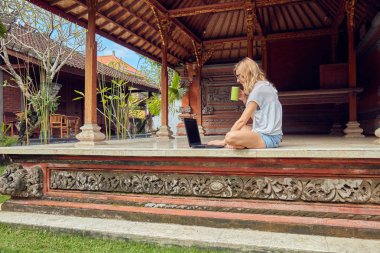 Bir ev verandada kahve / çay ve dizüstü bilgisayar ile Freelancer kız.