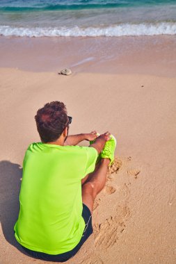 Sportsman stretching on a exotic tropical beach after jogging / 