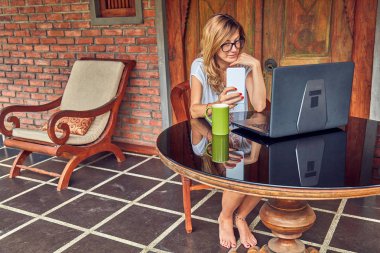 Akıllı telefon, kahve / çay ve dizüstü bilgisayar ile Freelancer kız bir ho