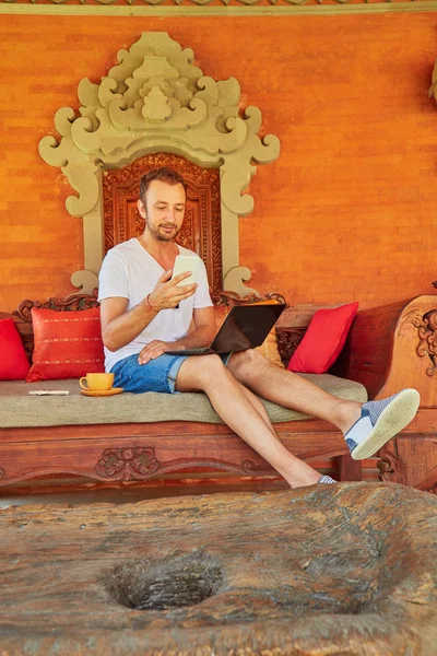 Hombre con café / té y portátil en un porche de casa . — Foto de Stock