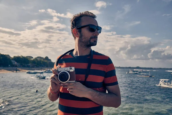 Man using vintage film camera on a ocean / sea vacation.