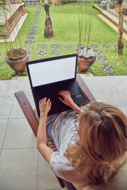 Kız bir ev veranda / terasta dizüstü bilgisayar kullanarak.