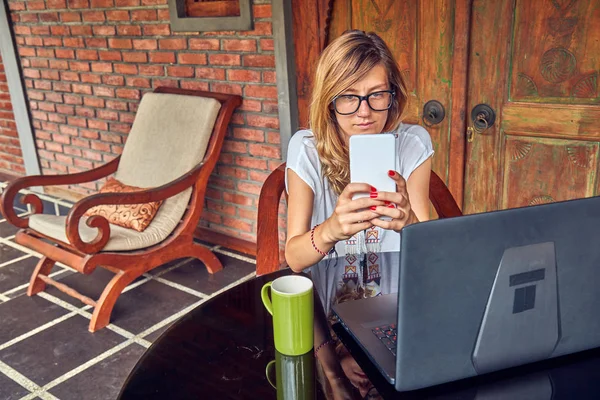 Freelancer meisje met smartphone, koffie/thee en laptop op een Ho — Stockfoto