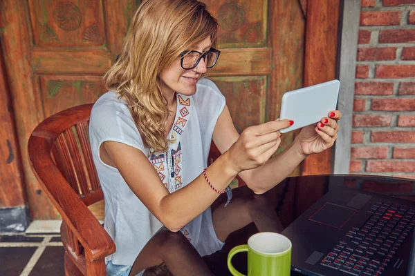 Фрілансер дівчина зі смартфоном, кавою / чаєм і ноутбуком на хо — стокове фото