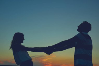 Gün batımı / gün doğumu saatinde bir çiftin siluetleri.