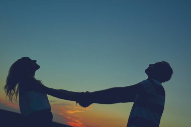 Gün batımı / gün doğumu saatinde bir çiftin siluetleri.