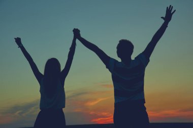 Gün batımı / gün doğumu saatinde bir çiftin siluetleri.
