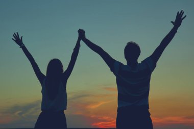 Gün batımı / gün doğumu saatinde bir çiftin siluetleri.