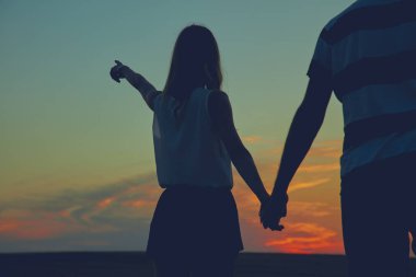 Gün batımı / gün doğumu saatinde bir çiftin siluetleri.