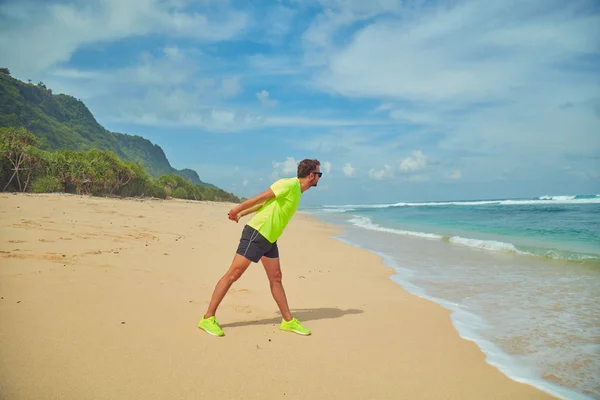 Sportsman peregangan di pantai berpasir tropis . — Stok Foto