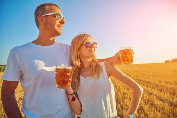 Young couple drinking beer outdoors and enjoying summertime.