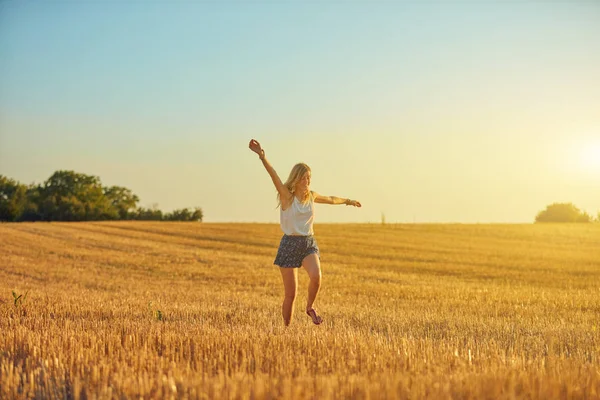 Sevimli genç kadın bir buğday tarlasında atlama. — Stok fotoğraf