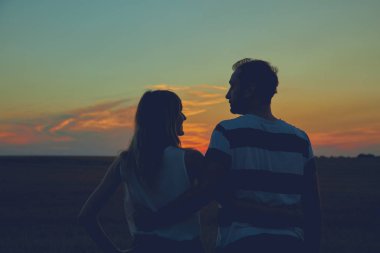 Gün batımı / gün doğumu saatinde bir çiftin siluetleri.