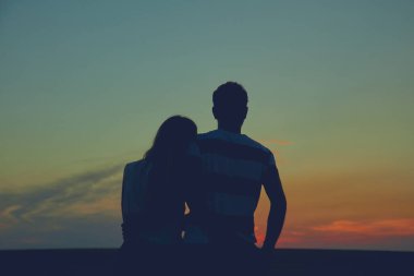 Gün batımı / gün doğumu saatinde bir çiftin siluetleri.
