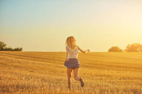 Sevimli genç kadın bir buğday tarlasında atlama. — Stok fotoğraf