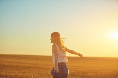 Sevimli genç kadın bir buğday tarlasında atlama.