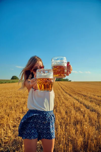 Boldog lány gazdaság üveg sört a nagy búza-mező. — Stock Fotó