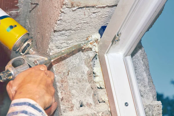 Construction worker puts expandable foam on the PVC window for i — Stock Photo, Image