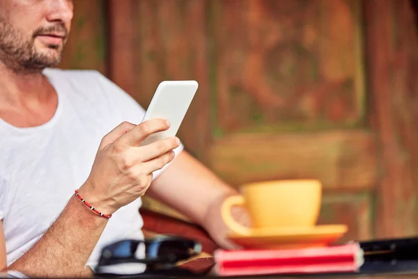 Homem com smartphone, café / chá e laptop em um alpendre . — Fotografia de Stock