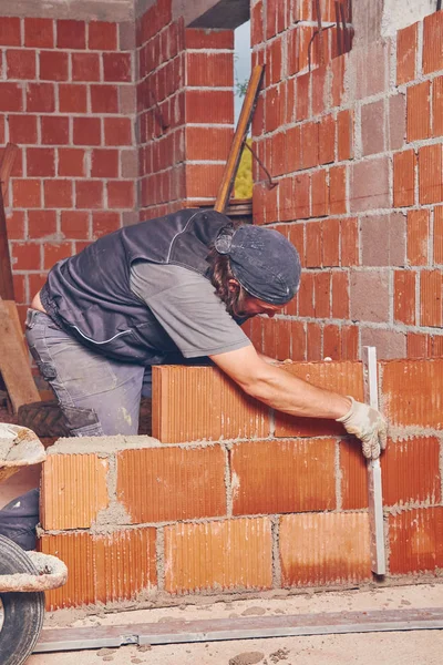 Rzeczywistej konstrukcji pracownik murowanie ściany w pomieszczeniu. — Zdjęcie stockowe