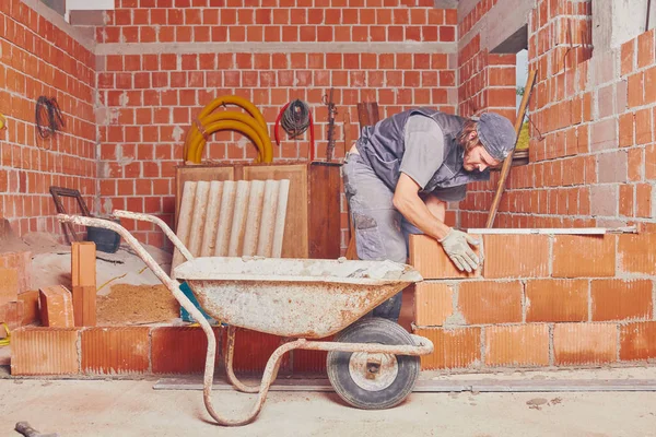 Real construction worker bricklaying the wall indoors. — Stock Photo, Image