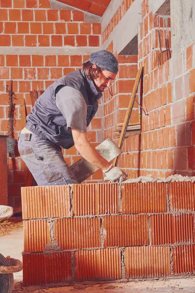 Real construction worker bricklaying the wall indoors. — Stock Photo, Image