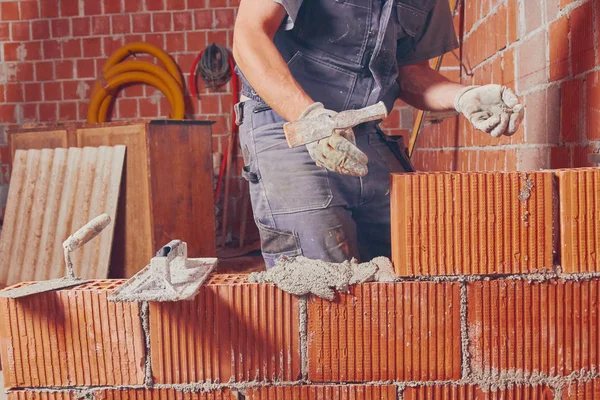 Real construction worker bricklaying the wall indoors.