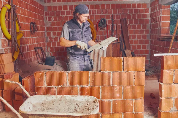 Véritable ouvrier de la construction maçonnant le mur à l'intérieur . — Photo