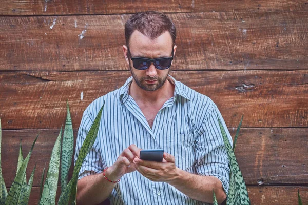 Hombre con gafas de sol y camisa de verano con smartphone . —  Fotos de Stock