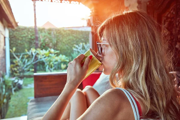 Girl enjoying morning coffee on the garden sofa. — Stock Photo, Image