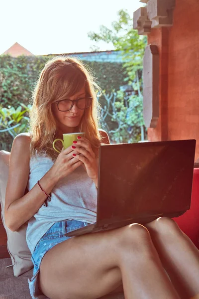 Freelancer girl working on a vacation / at home patio porch.