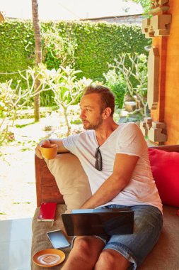 Bir ev verandada kahve / çay ve dizüstü bilgisayar ile Man.