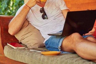 Bir ev verandada kahve / çay ve dizüstü bilgisayar ile Man.