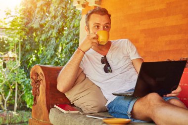 Bir ev verandada kahve / çay ve dizüstü bilgisayar ile Man.