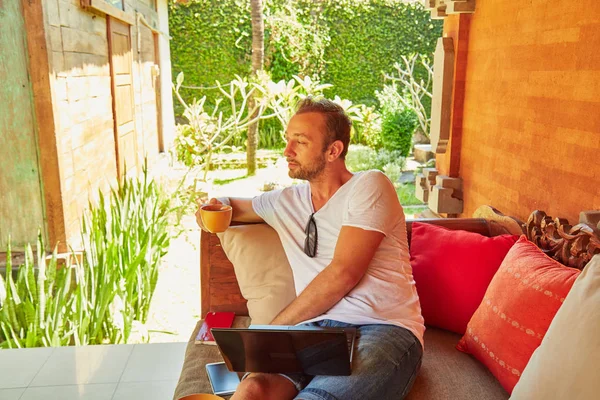 Man with coffee / tea and laptop on a home porch. — Stock Photo, Image