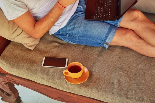 Hombre con café / té y portátil en un porche de casa . — Foto de Stock