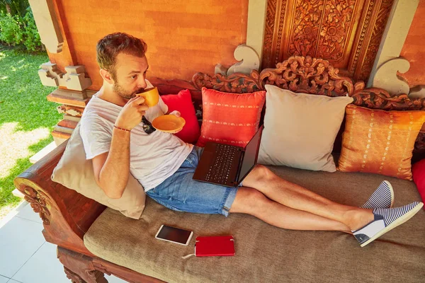 Hombre con café / té y portátil en un porche de casa . — Foto de Stock