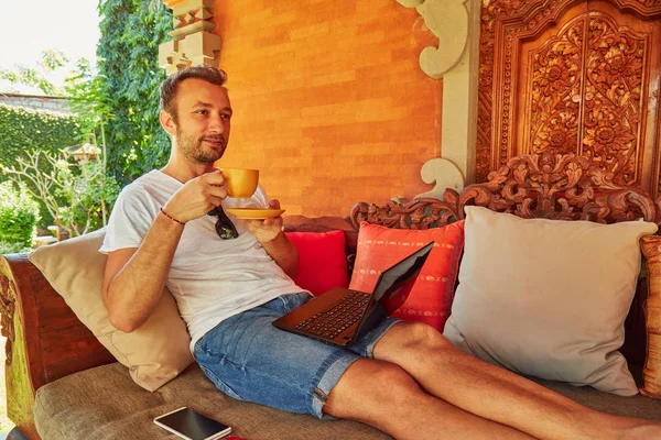 Hombre con café / té y portátil en un porche de casa . — Foto de Stock